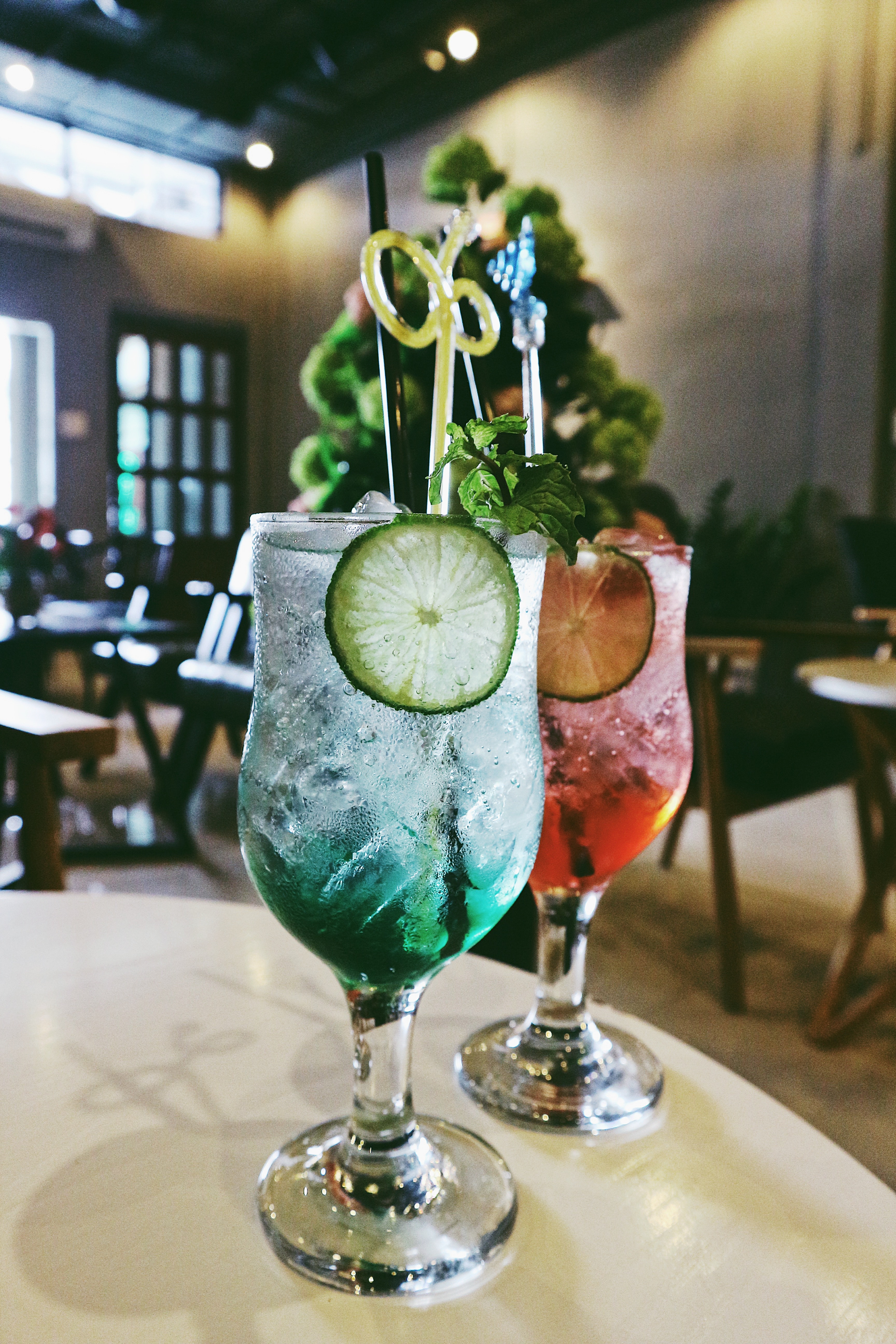 Two cocktailglasses filled with a drink on a table.