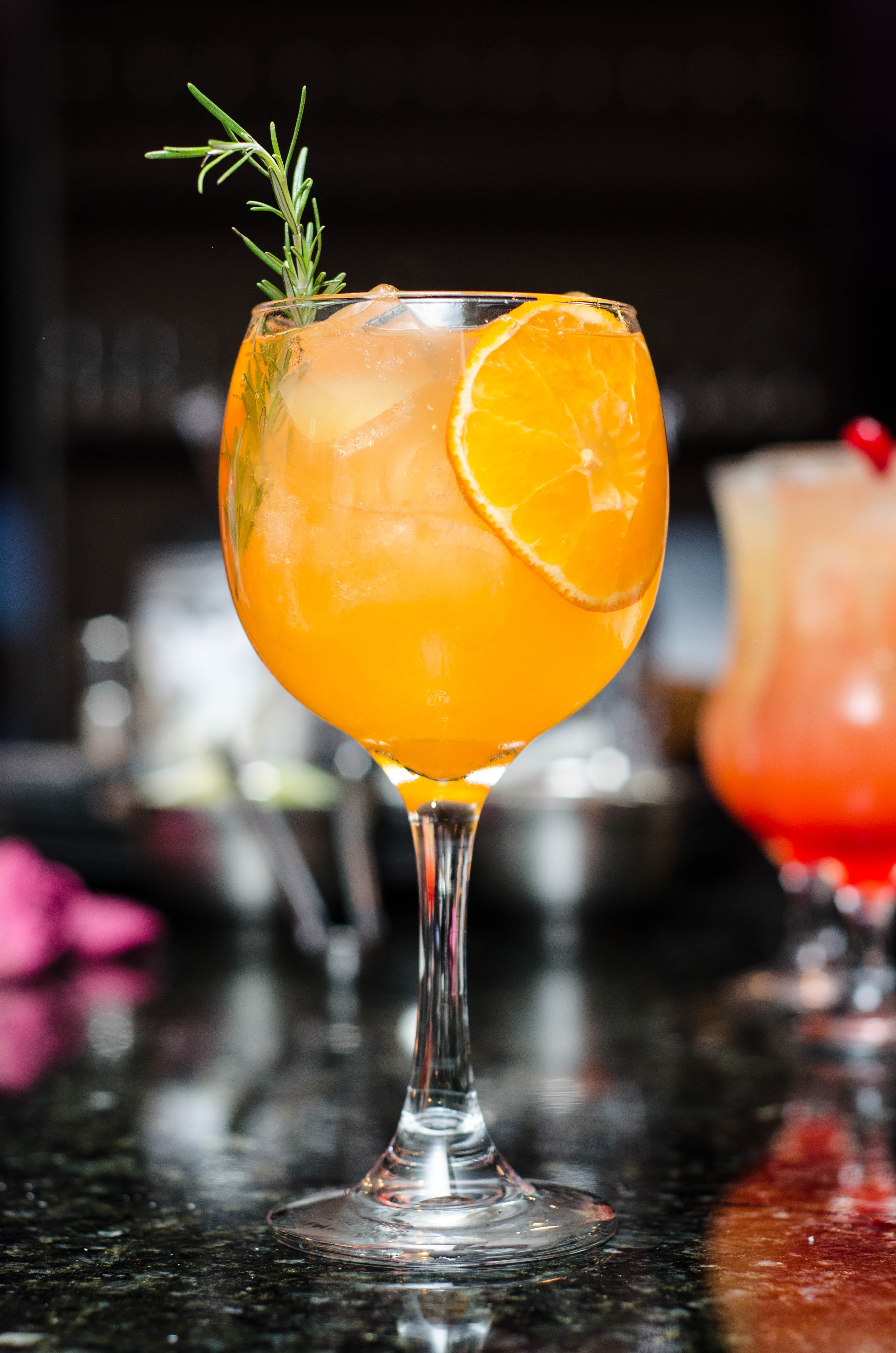 One apertif glass filled with an orange drink on a table.